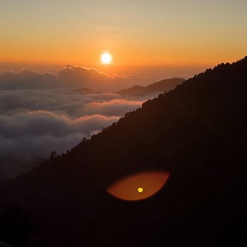 Sun rising over a sea of clouds and mountain ridges