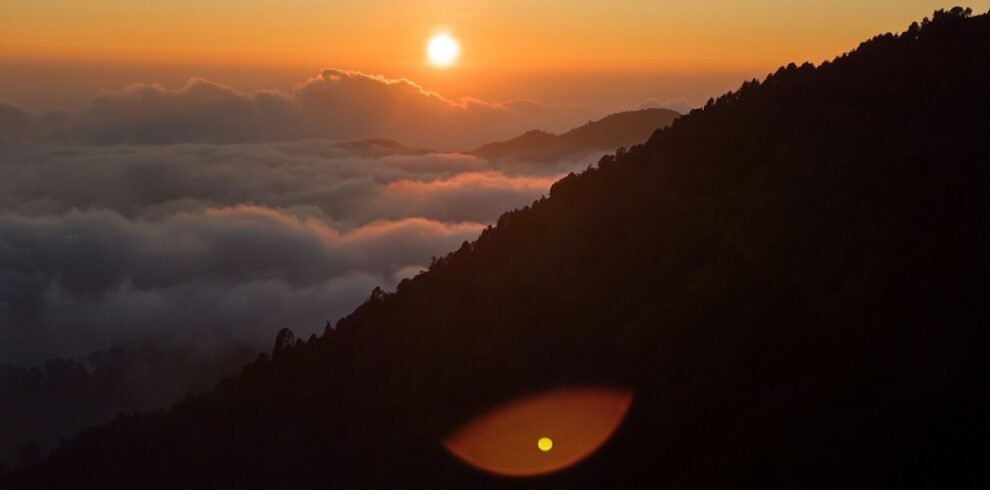 Sun rising over a sea of clouds and mountain ridges