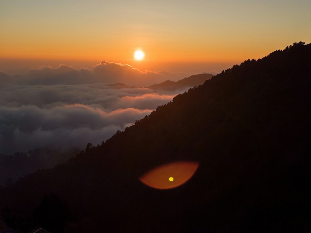 Sun rising over a sea of clouds and mountain ridges